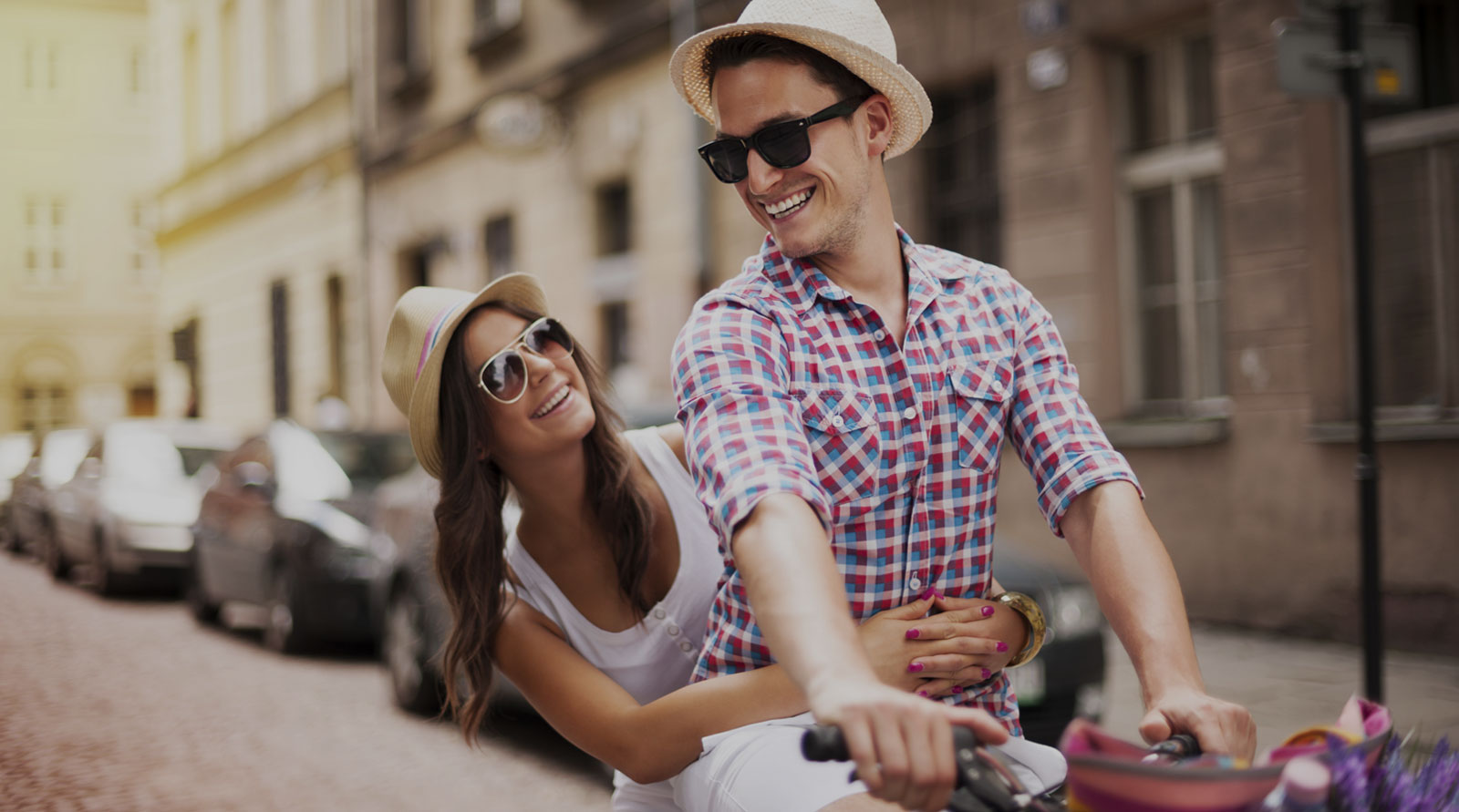 Couple enjoying a bike ride in a sunny street, promoting a proactive lifestyle and healthy choices.