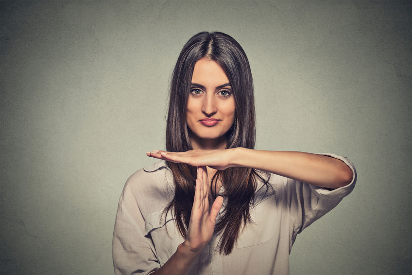 Woman making a "stop" gesture with hands, promoting stress management and well-being in health insurance context.