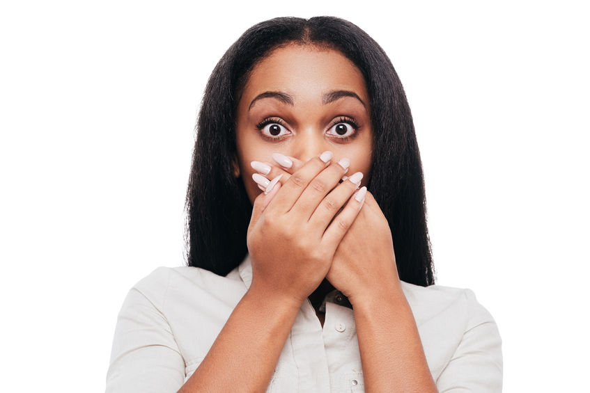 Woman covering her mouth with wide eyes, expressing surprise or concern, relating to health and wellness themes of setting boundaries and self-care.