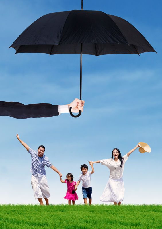 Family enjoying a sunny day outdoors under a large black umbrella, symbolizing protection and wellness, relevant to health insurance and family coverage.
