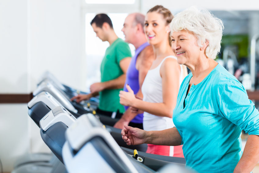 Group of diverse individuals, including an older woman, exercising on treadmills, promoting fitness discounts and wellness services from Optimized Health Plans.