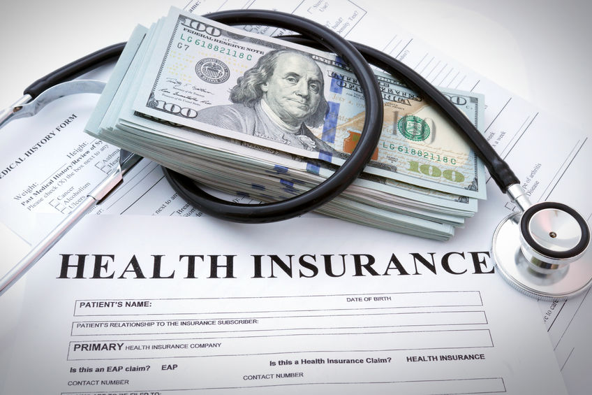 Stacks of cash with a stethoscope and health insurance forms, emphasizing affordable health insurance solutions and financial planning for individuals and small businesses.