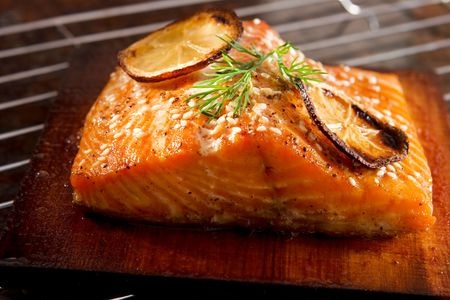 Grilled salmon fillet garnished with lemon slices and herbs, highlighting healthy fatty fish options for better health.