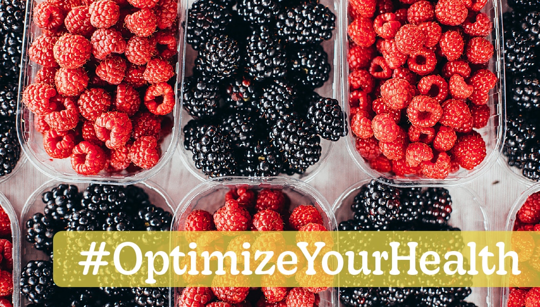 Fresh red raspberries and blackberries in clear containers with a "#OptimizeYourHealth" banner, emphasizing the health benefits of berries.