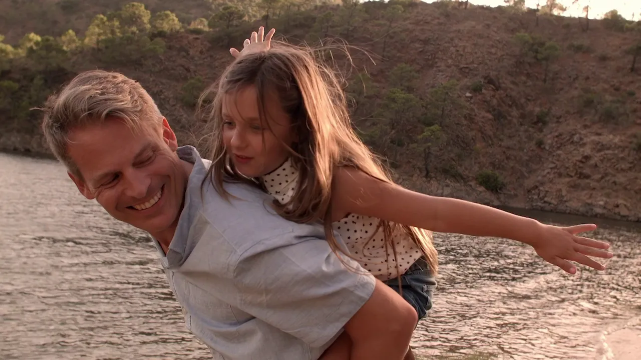 Father and daughter enjoying a playful moment by the water, emphasizing family connections and outdoor activities.