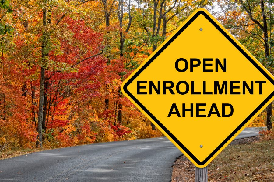 Open enrollment ahead sign against vibrant autumn foliage, symbolizing the upcoming health insurance enrollment period.